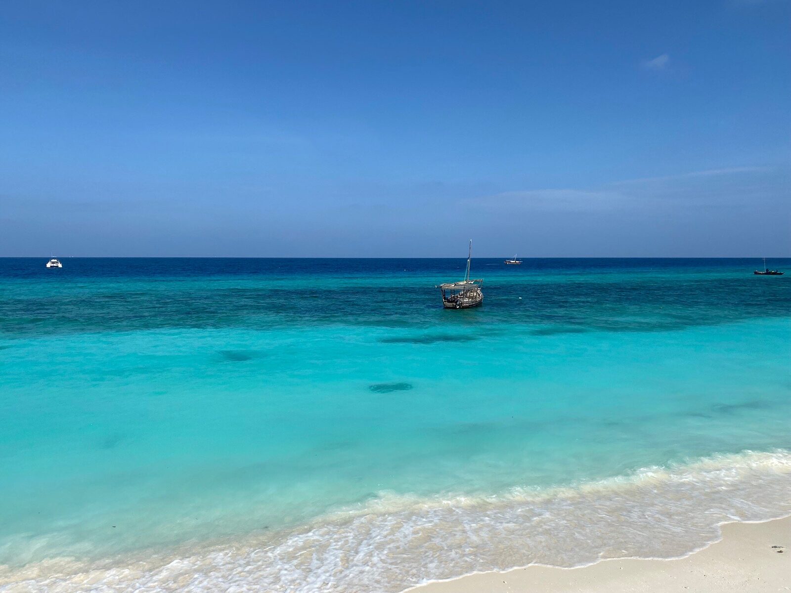 Anchored dhow in turquoise water near a Zanzibar island
