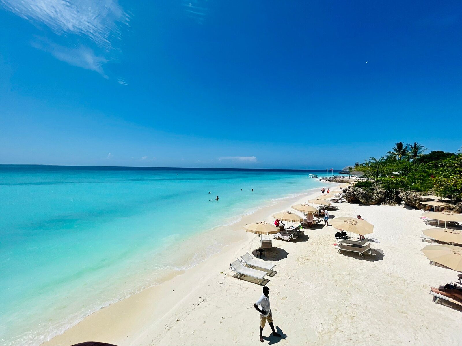 Beach loungers and umbrellas beside a turquoise Zanzibar bay