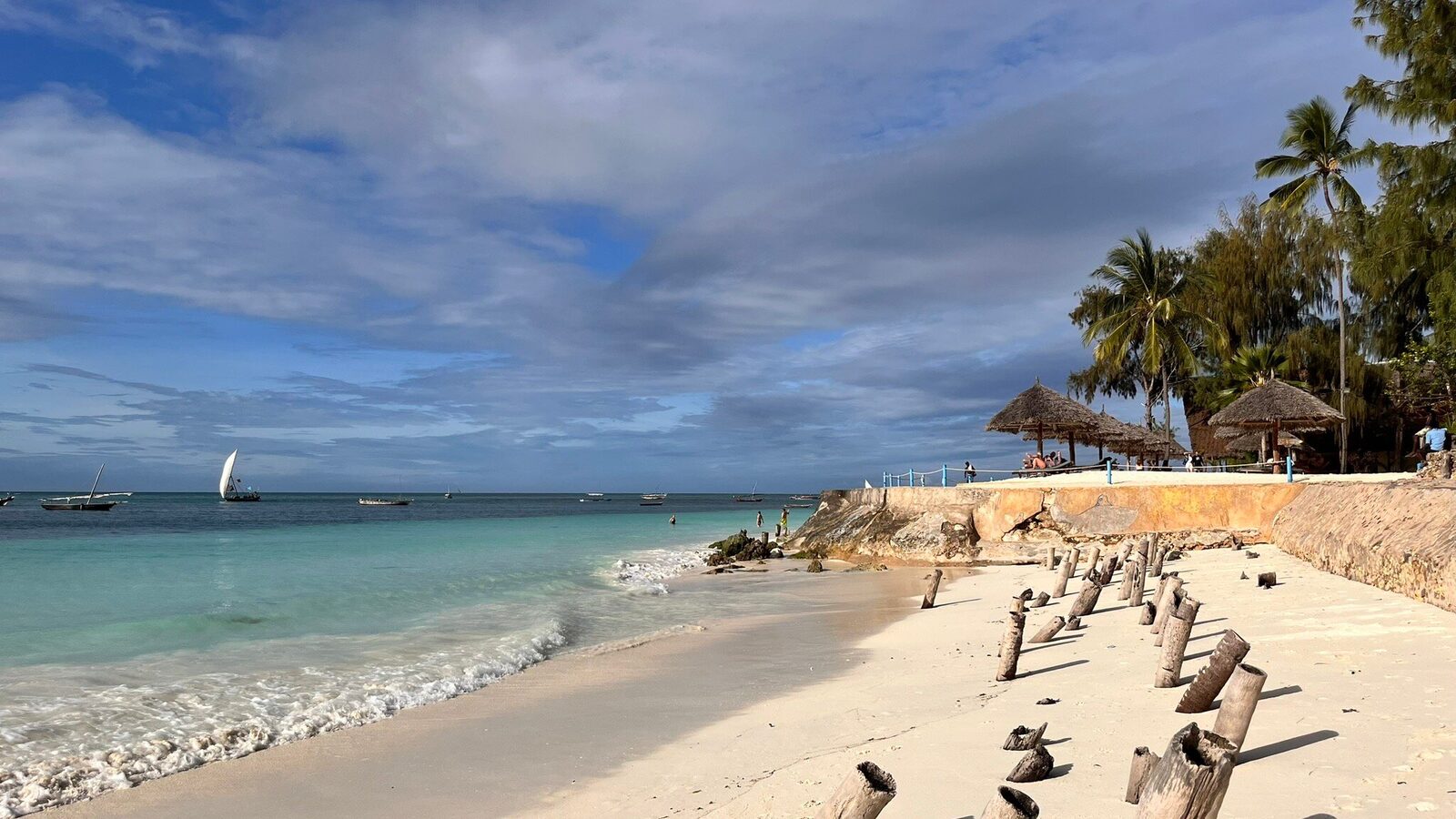 Dhow sailboat beside a Zanzibar beach seawall