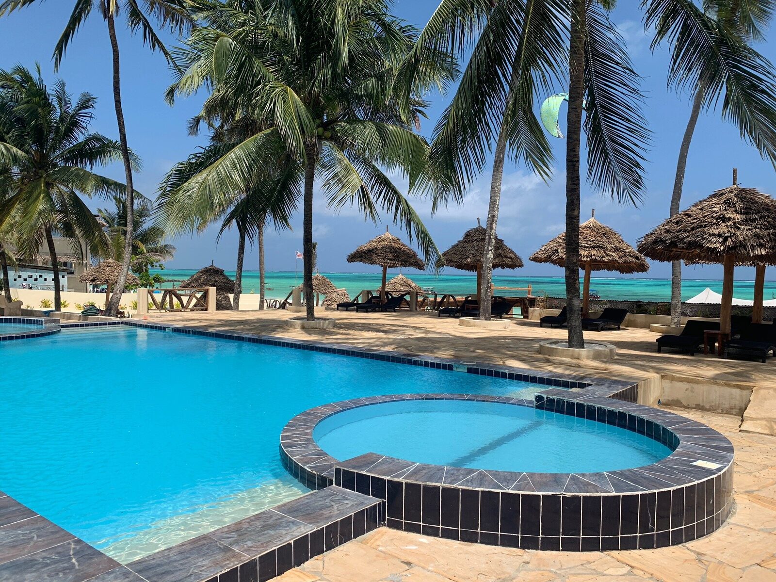 Beachfront resort pool with thatched umbrellas in Zanzibar