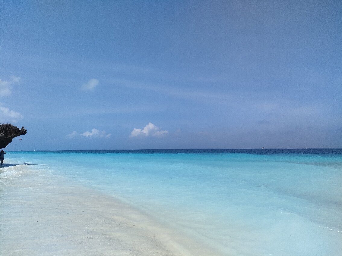 Calm blue sea below a rocky coastal overhang at Mangapwani
