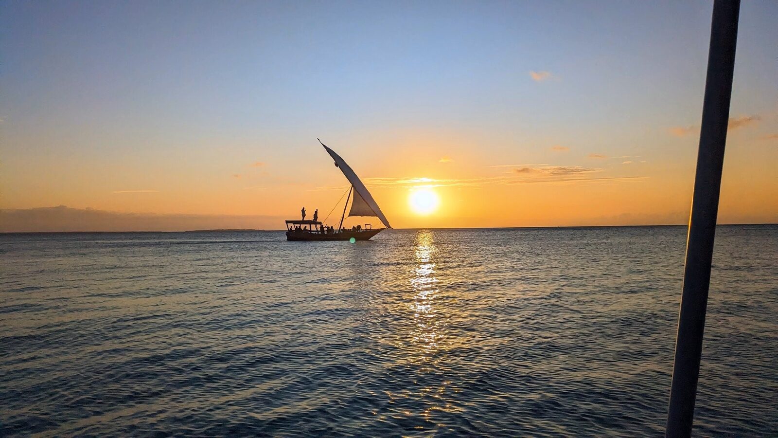 Traditional dhow sailboat cruising at sunset off Zanzibar