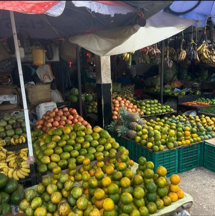 Oranges, bananas and pineapple piled at a market stall