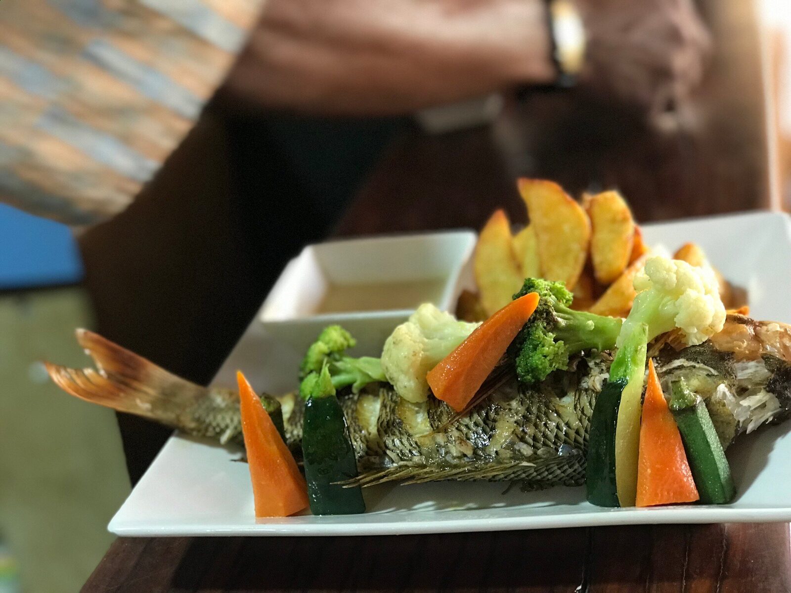 Whole grilled fish with vegetables at a Swahili cuisine tasting